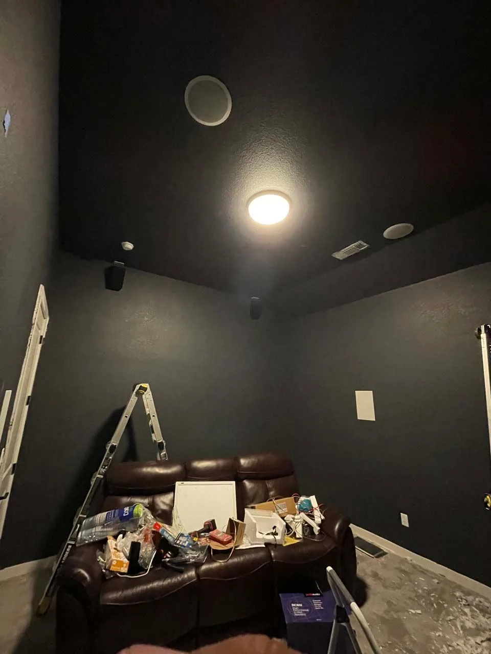 A person is installing a speaker in a wall with a drill.