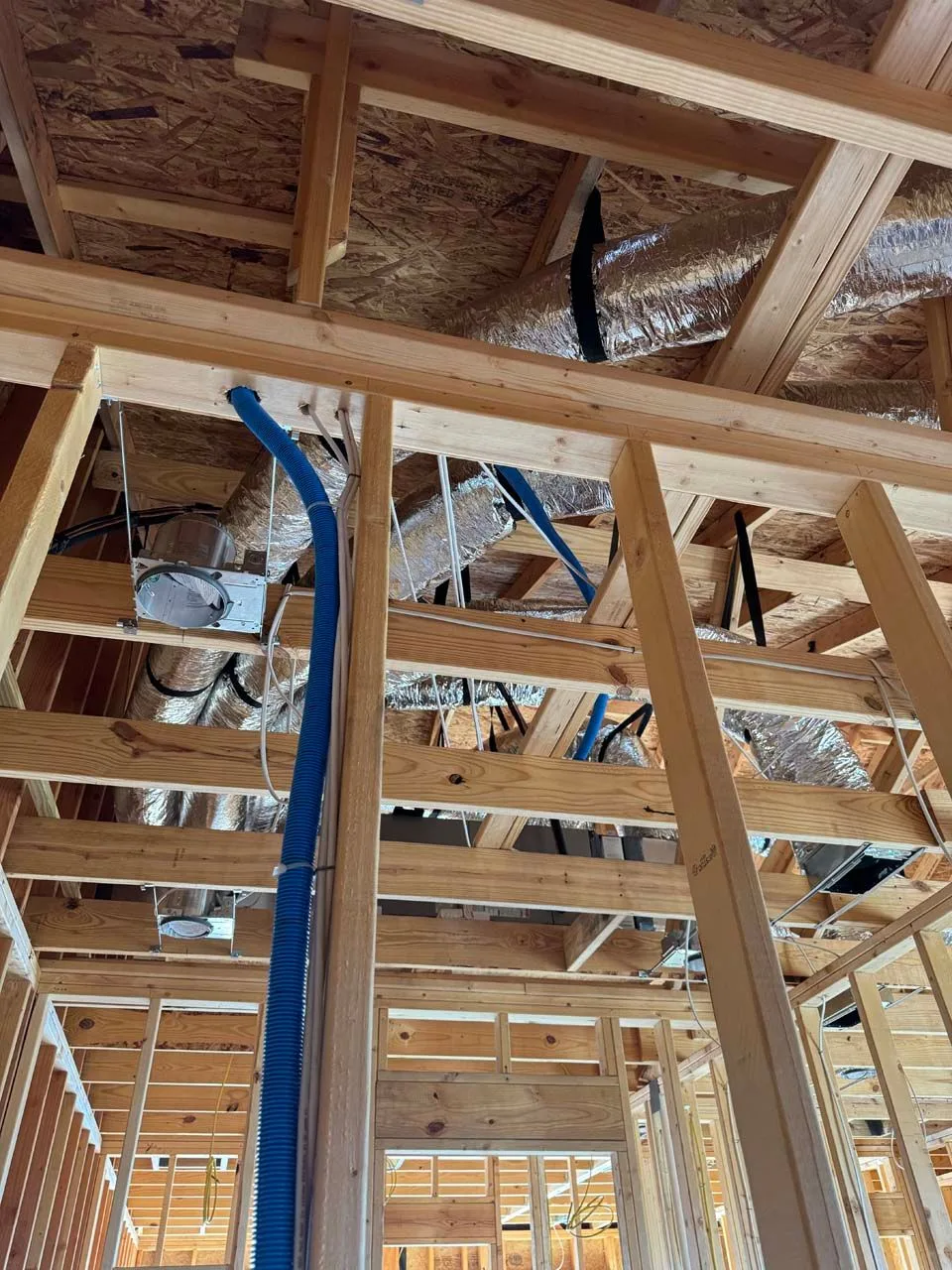 A room in a house under construction with a lot of wires hanging from the ceiling.